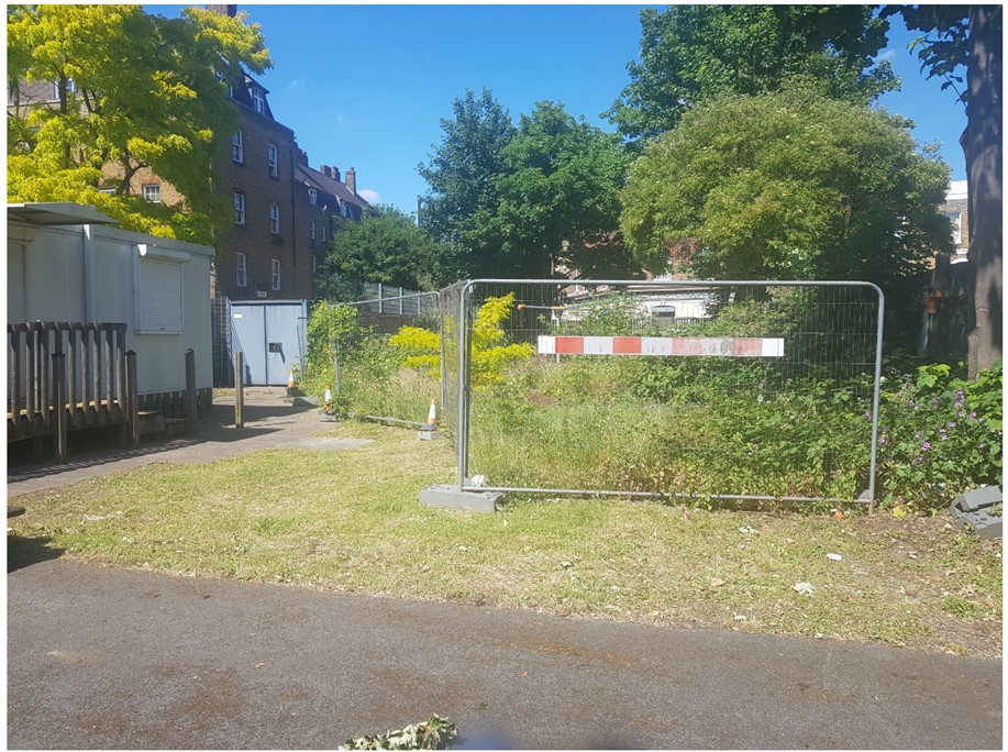 Fredericks Playground site as it appeared when closed - tall metal fences with weeds and long grass behind them 
